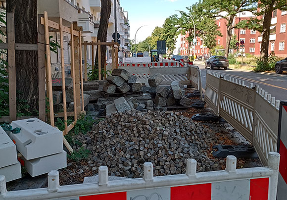 Das Foto zeigt verschiedene Materiallager: Mosaikpflaster, Bordsteine.